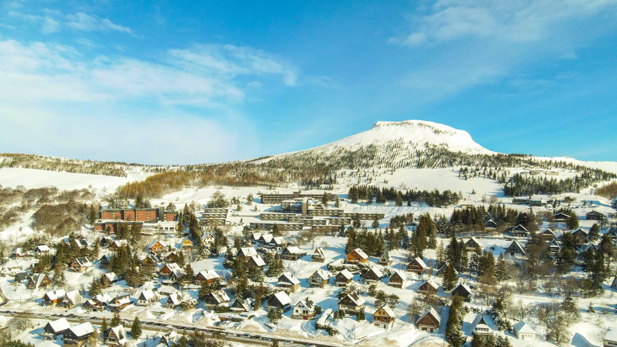 Super Besse : Le Puy de Chambourguet veille sur un village de chalets enneigés, un tableau féérique.