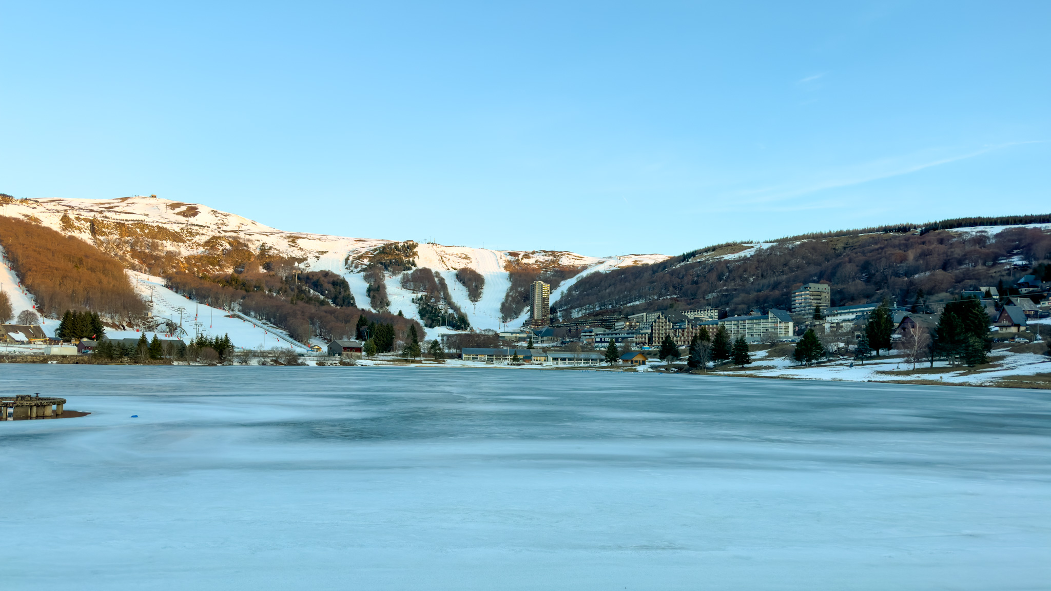 Super Besse : Vue panoramique du Lac des Hermines sur le centre-ville ensoleillé